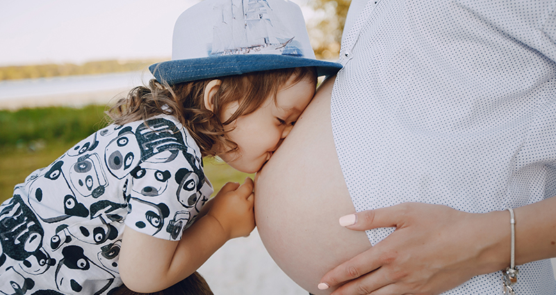 Un bimbo piccolo che bacia la mamma sul pancione