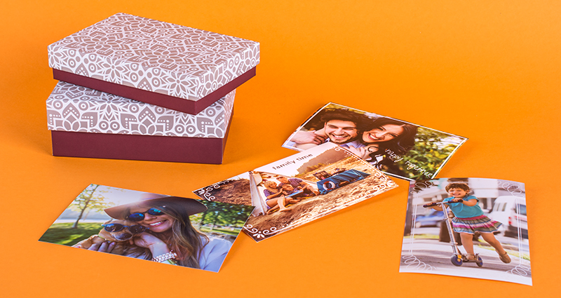 Boxes for photo prints with arabesque theme in two sizes, next to them spread prints – orange background.
