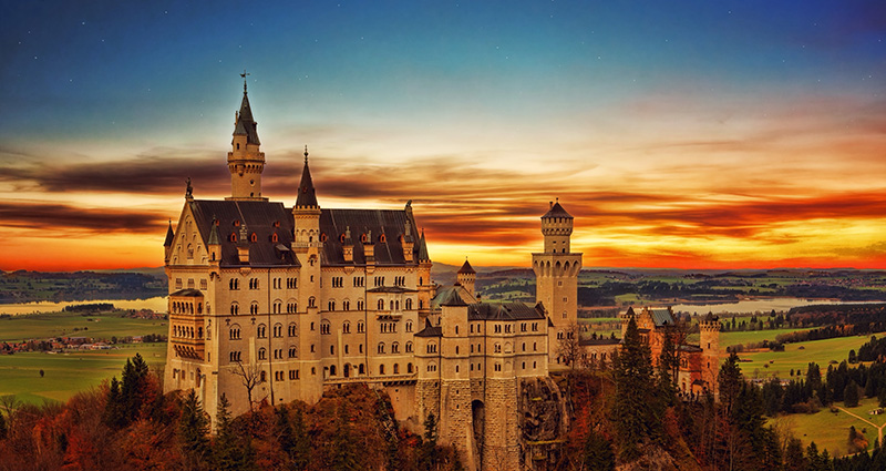 Das aus der Ferne gesehene Schloss Neuschwanstein bei Sonnenuntergang.