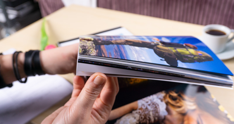 Close-up on female’s hands going through pages of the Starbook. Bright coffee table with a coffee cup on it in the background