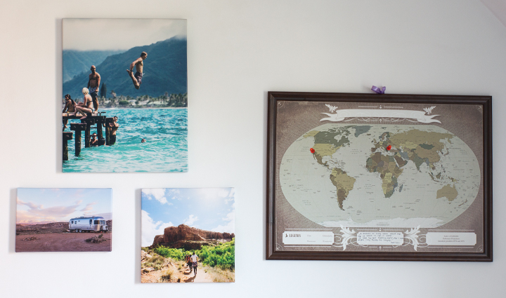 Plusieurs toiles photo de voyage accrochées au mur à côté une carte géographique.