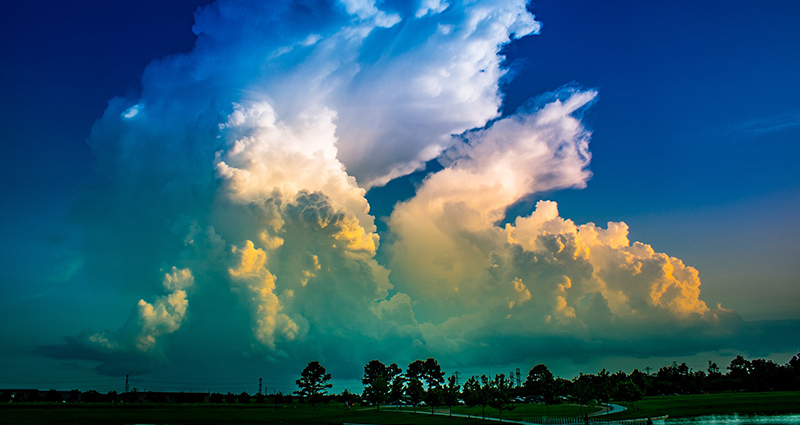 Bunte Wolken über den Bäumen und dem Zuflussgebiet