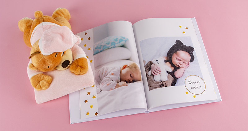 Fotolibro con fotos de la sesión de bebés, al lado del libro – un peluche.