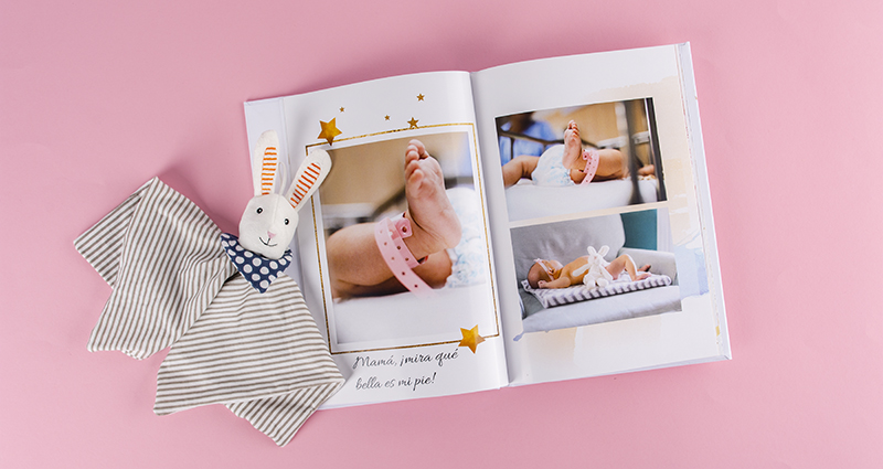 Fotolibro con fotos de un bebé, una mascota al lado del libro.