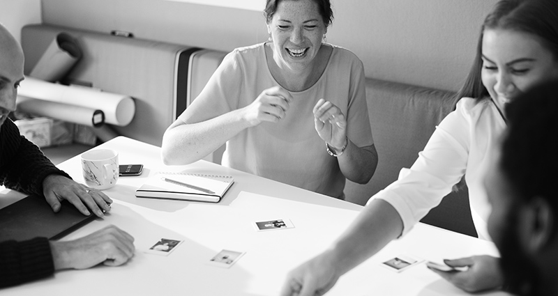 Grupo de personas sentado a la mesa y riéndose durante los talleres de fotos.