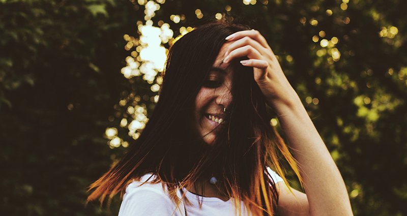 Laughing brunette, trees in the background