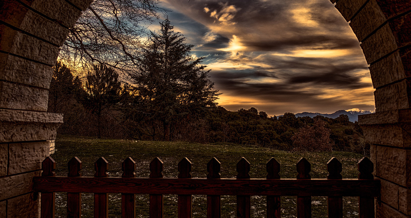 Meadow, wood and the sunset captured through a building arch