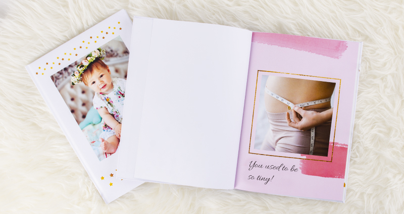 Newborn baby’s photo book with a picture of a pregnant woman’s belly on the first page