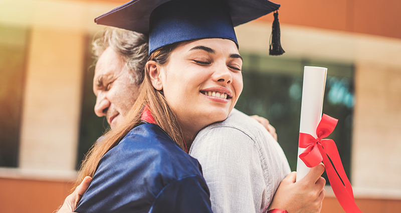 Un padre che abbraccia sua figlia dopo la laurea all'università.