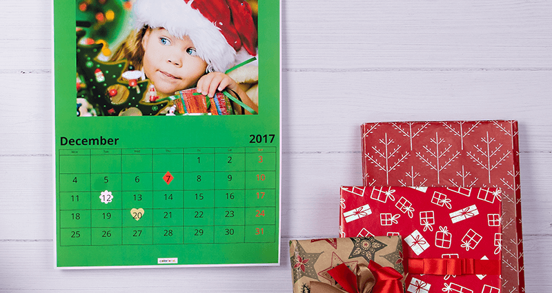 Un calendrier personnalisé avec paquet cadeau  et décoration à côté.