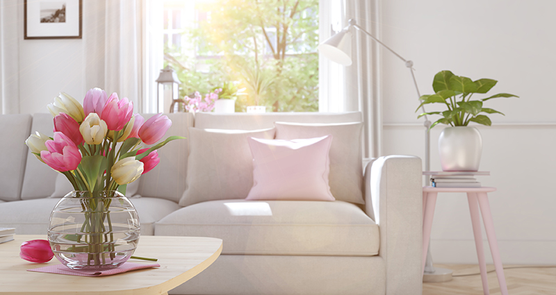 Photo of a bright living room with a vase of pink and white flowers on the coffee table.