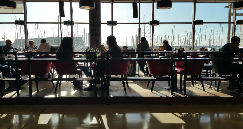 Fotografie kavárny se slunečními paprsky, které procházejí velkými okny a vrhají stíny na podlahu