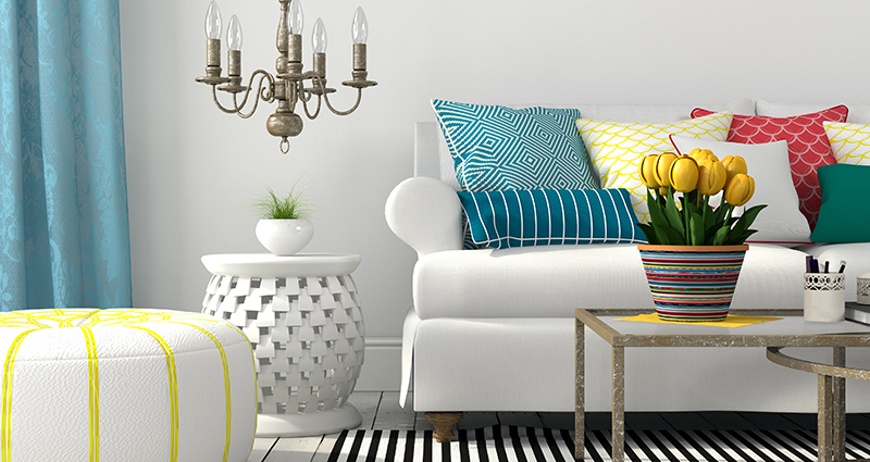 Ein Foto von einem hellen Wohnzimmer mit bunten Details mit verschiedenen Mustern - Kissen, Sitzpuff, Vorhängen und Teppich.