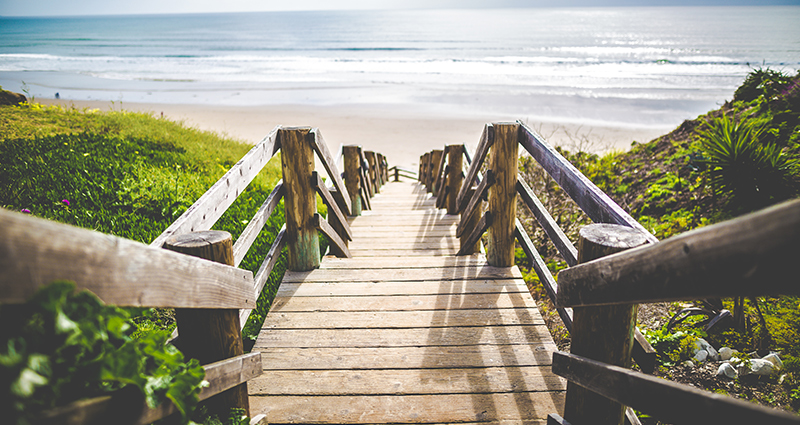 Bild von der Holztreppe, im Hintergrund das Meer 