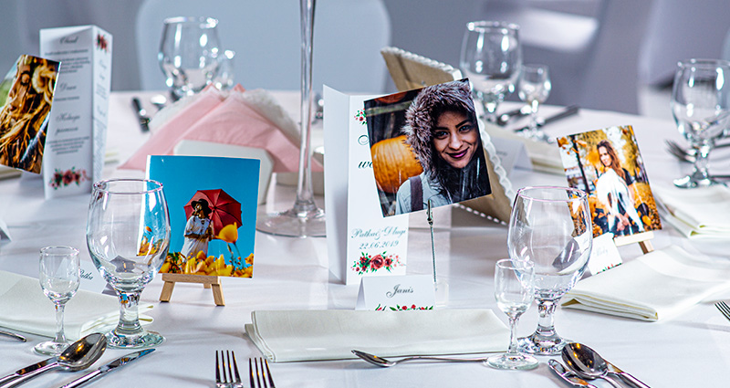 Marcasitios de boda en forma de instafotos, y con las fotos de invitados a la boda en unos estantes con un clips o mini caballetes de madera en la mesa de la boda.