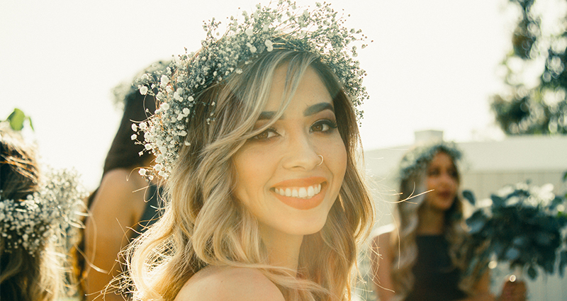 Une fille blande souriante , habilllée en  couronne de fleurs blanches