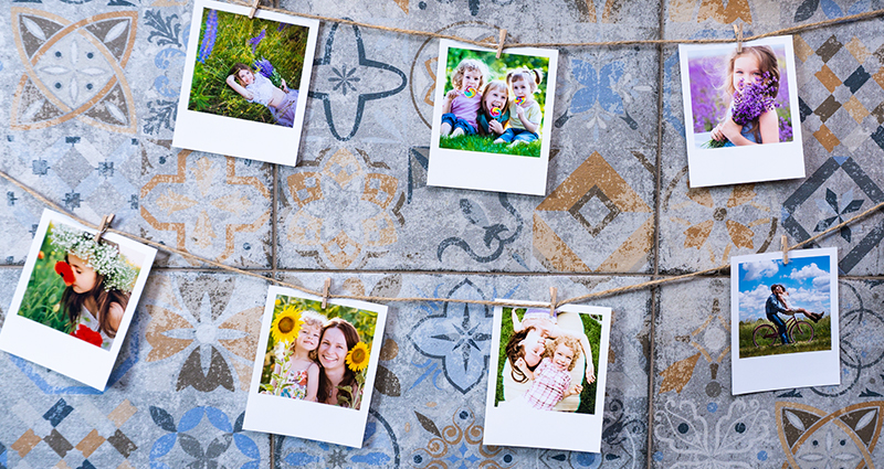 Spring retro prints hanging on a twine with mosaic tiles in the background. Next to it a vase with spring flowers.