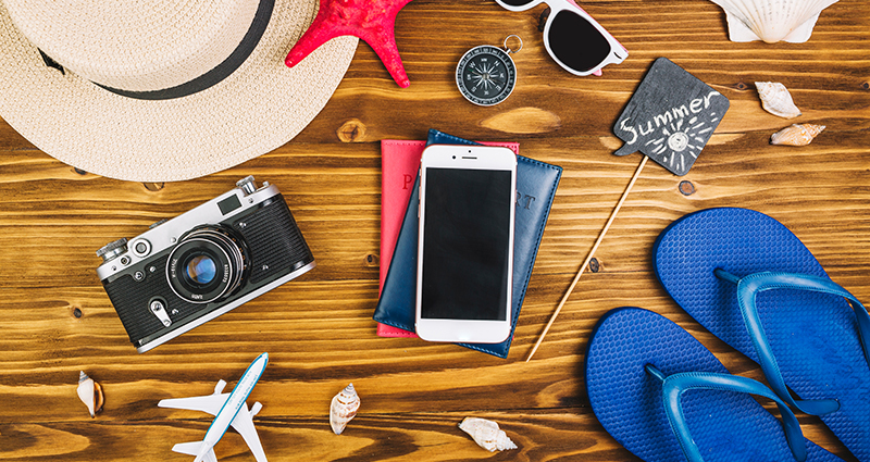 Sommerliche Dekoration mit Fotoapparat, Strohhut, Flip-Flops, Seestern und Muscheln