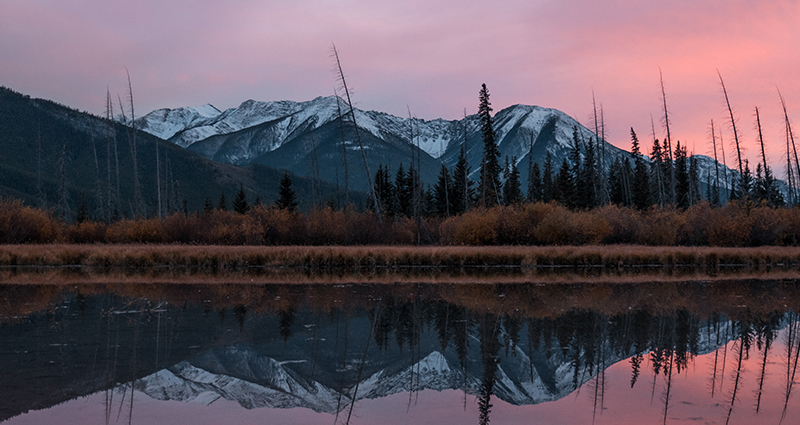 Sunset in mountains and their reflection on the lake’s surface