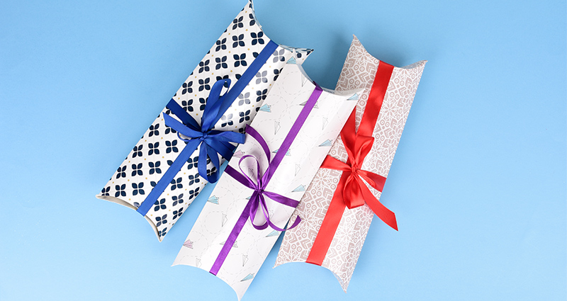 Drei tubenförmige Geschenkverpackungen mit Schleife für Fotokalender auf blauem Hintergrund