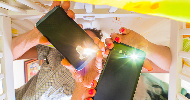 Two people holding smartphones and taking photos of a baby in a crib with flashlight on – photo from the baby’s view.