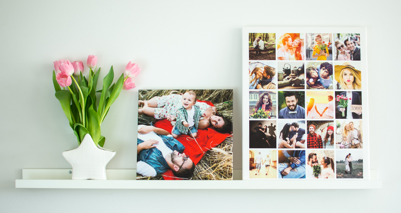 Two photo canvases (one of which is square with a single photo and the other one is vertical with a collage) on a white shelf. Next to that a bouquet of pink tulips in a vase shaped like a star.