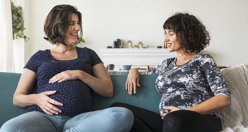 Two pregnant women on a sofa