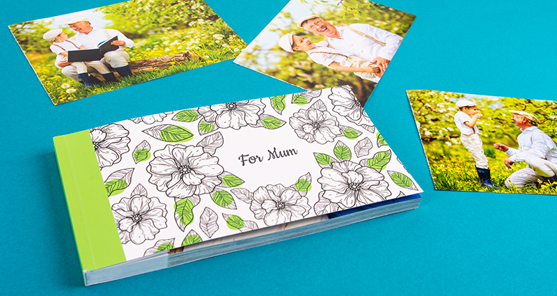 Two sharebooks with the Old fashioned flowers cover lying next to photos of a grandfather playing with his grandchild.