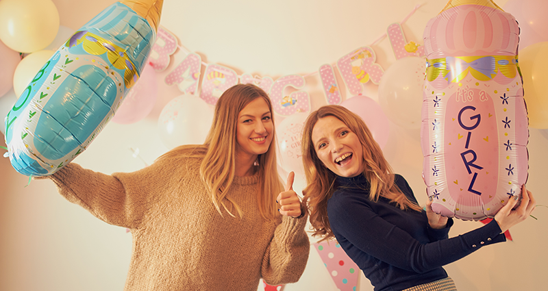 Due donne con dei palloncini a forma di biberon