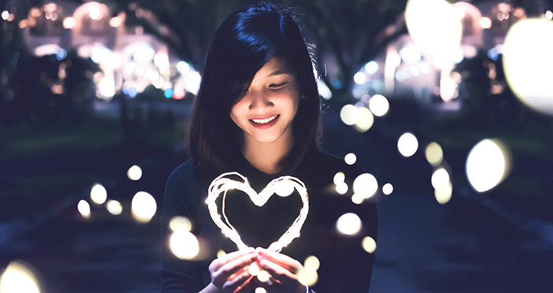 Una mujer tomando un corazón iluminado. 