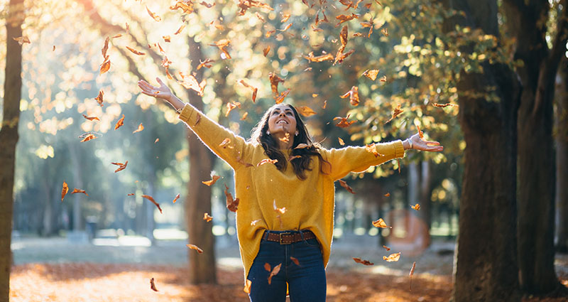 Una mujer posando para la fotografía de hojas de otoño