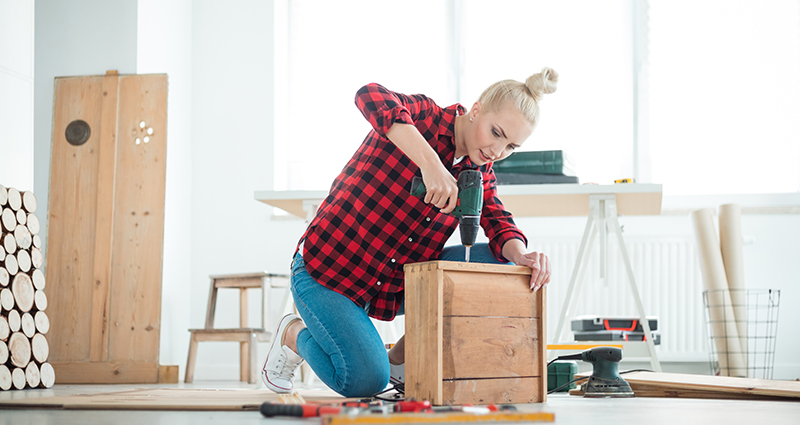 Woman putting a dresser together in a bright room.