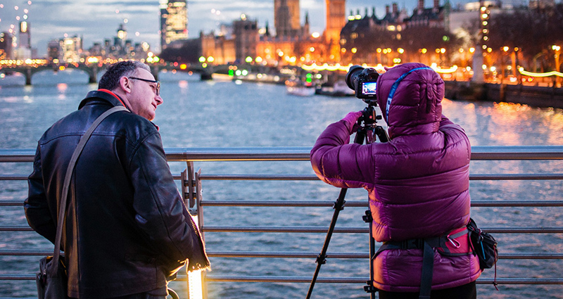 Une femme qui prend leds photos d’un pont. A côté un homme qui la regarde.