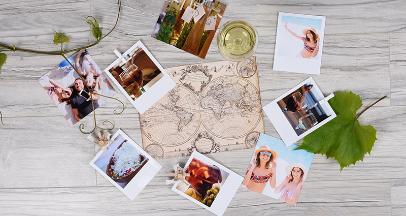 World map lying next to insta photos, retro prints with wooden paper clips and maple twigs