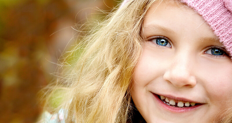 Zoom into a face of a big-eyed girl in pink hat.