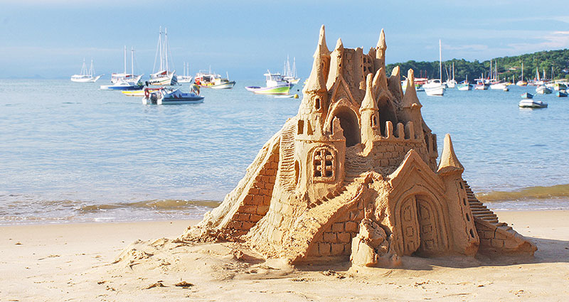 Lighted castle one the sand in the foreground.