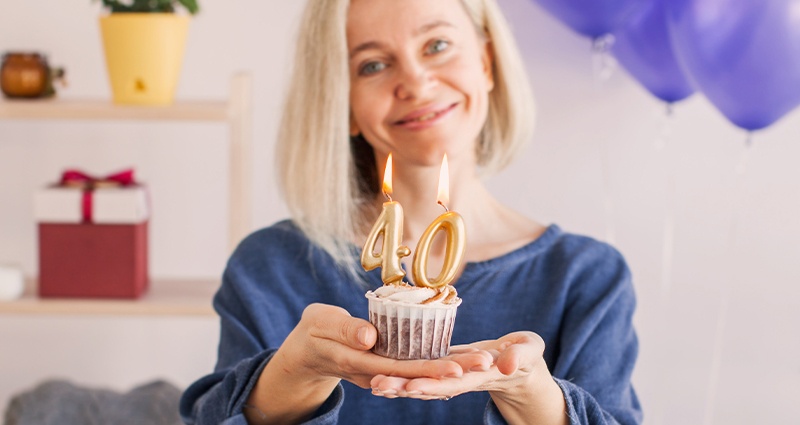 Smiling woman with cupcake and candles 40 - a symbolic celebration of a 40th birthday. A unique 40th birthday gift idea for her - personal, emotional and joyful.