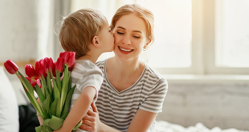 Een zoon die zijn moeder bloemen geeft en haar een fijne Moederdag wenst