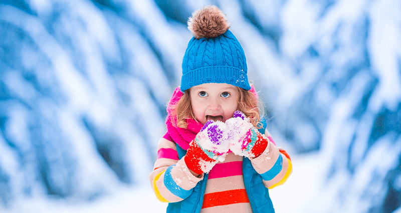 Una bambina in montagna che gioca con la neve