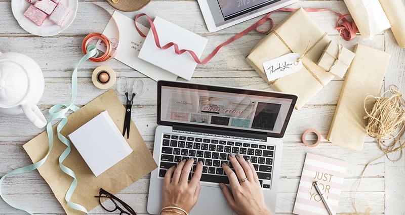 A signature of a laptop surrounded by paper and ribbons.