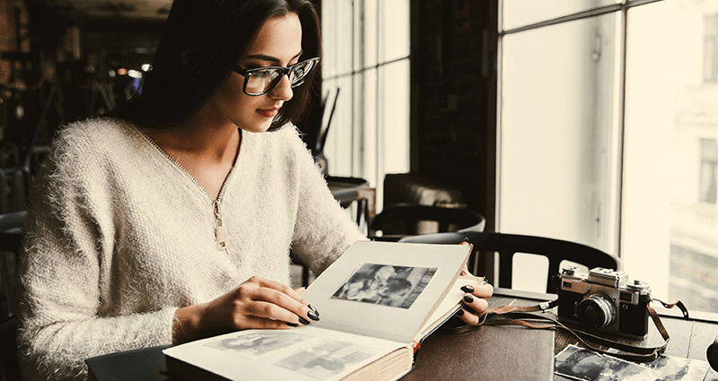 A woman is flipping through a photo book. Year in review photo book