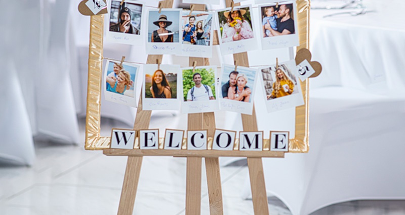 Close-up on a handmade personalised board with photos of the guests near the numbers of specific tables at the wedding ballroom