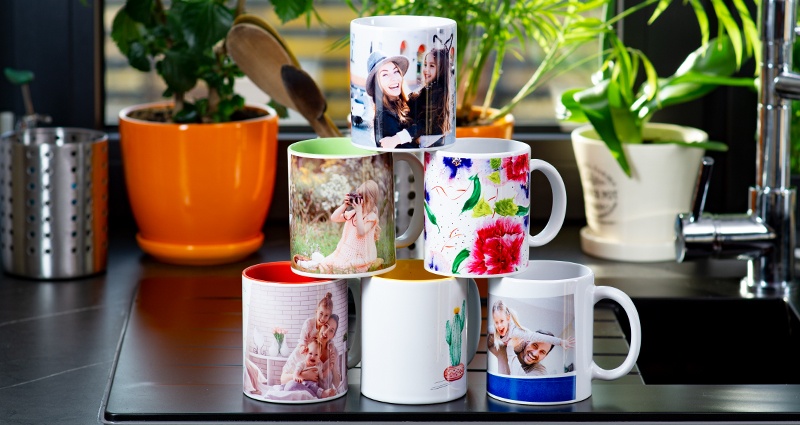 Coloured spring themed mugs arranged in a pyramid on a kitchen sink. Window and plants in the background.