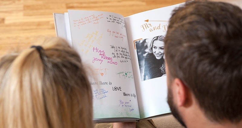 Pareja sentada en el sofá y mirando el libro de visitas, foto de la parte posterior. 