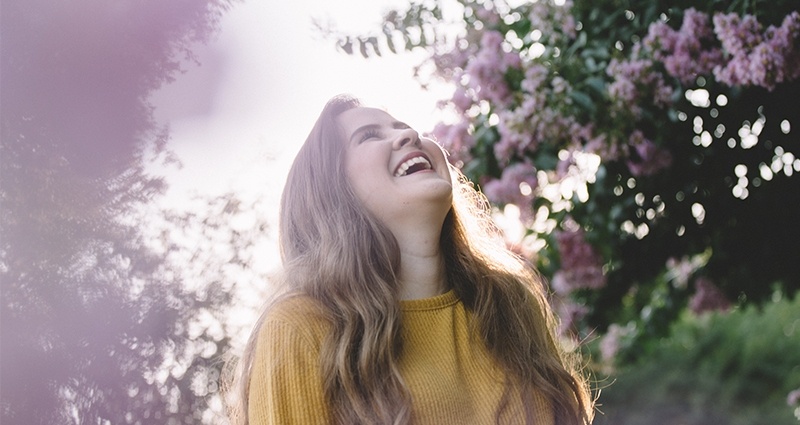 Lachende vrouw tussen bloeiende bomen.