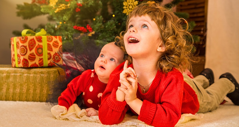 Two children lying under a Christmas tree