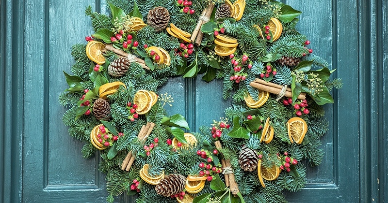 Couronne avec des citrons, de la cannelle et des pommes de pin accrochée sur la porte.